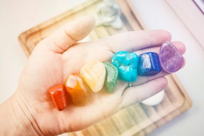 Woman hand sowing all seven color chakra crystal stones. Chakra