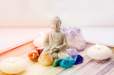 All seven chakra colors crystals stones around sitting Buddha fi